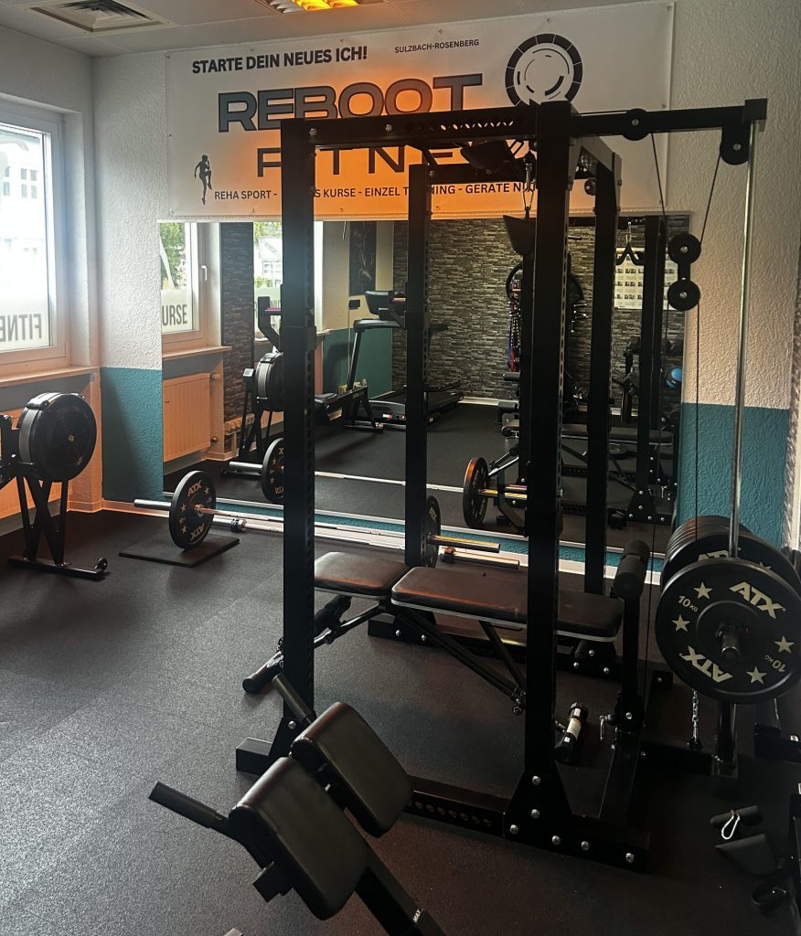 rehasport-training-reboot-fitness-sulzbac Trainingsbereich bei Reboot Fitness in Sulzbach-Rosenberg für Rehasport, Krafttraining und Einzeltraining mit Blick auf das Firmenlogo.